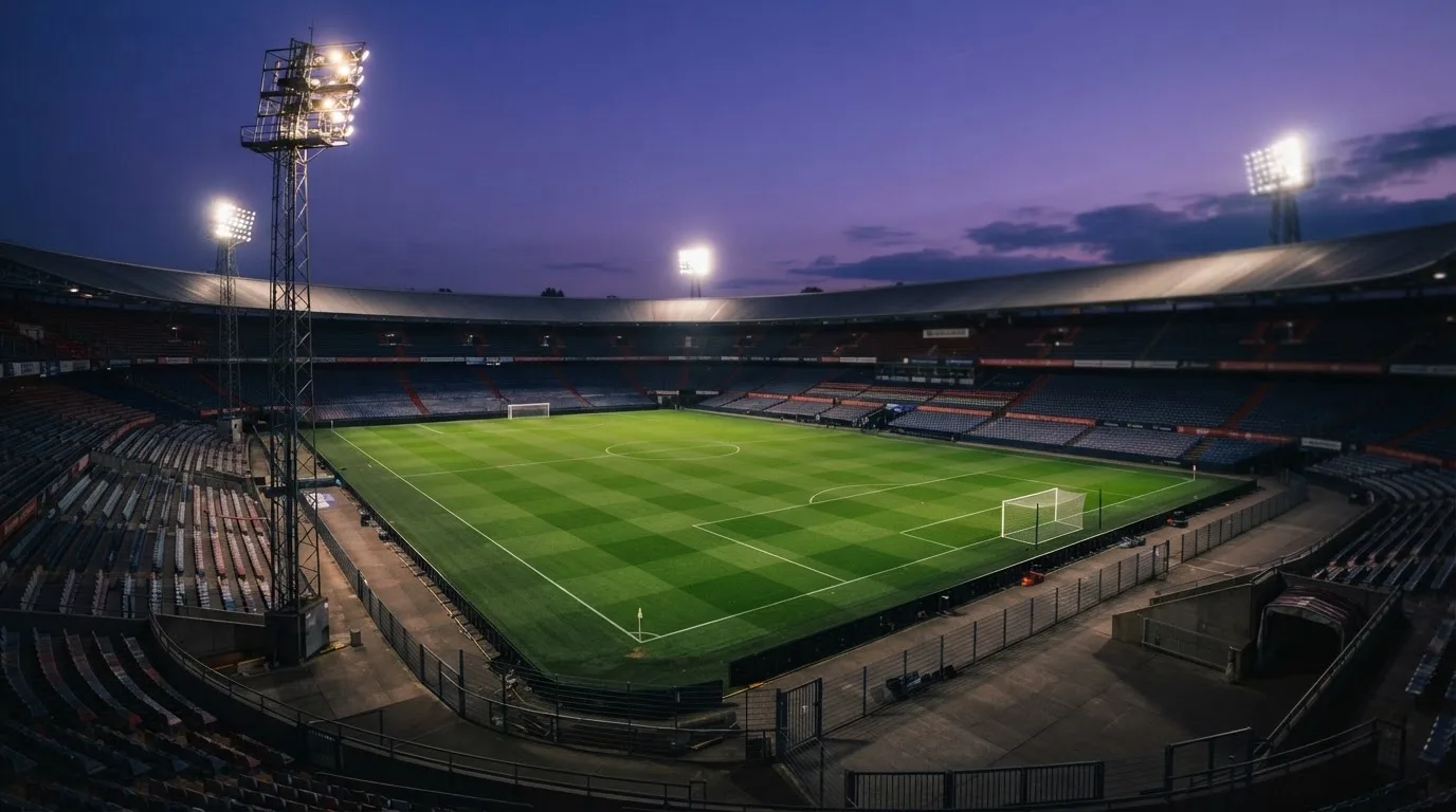 An empty football stadium with floodlight masts at dusk