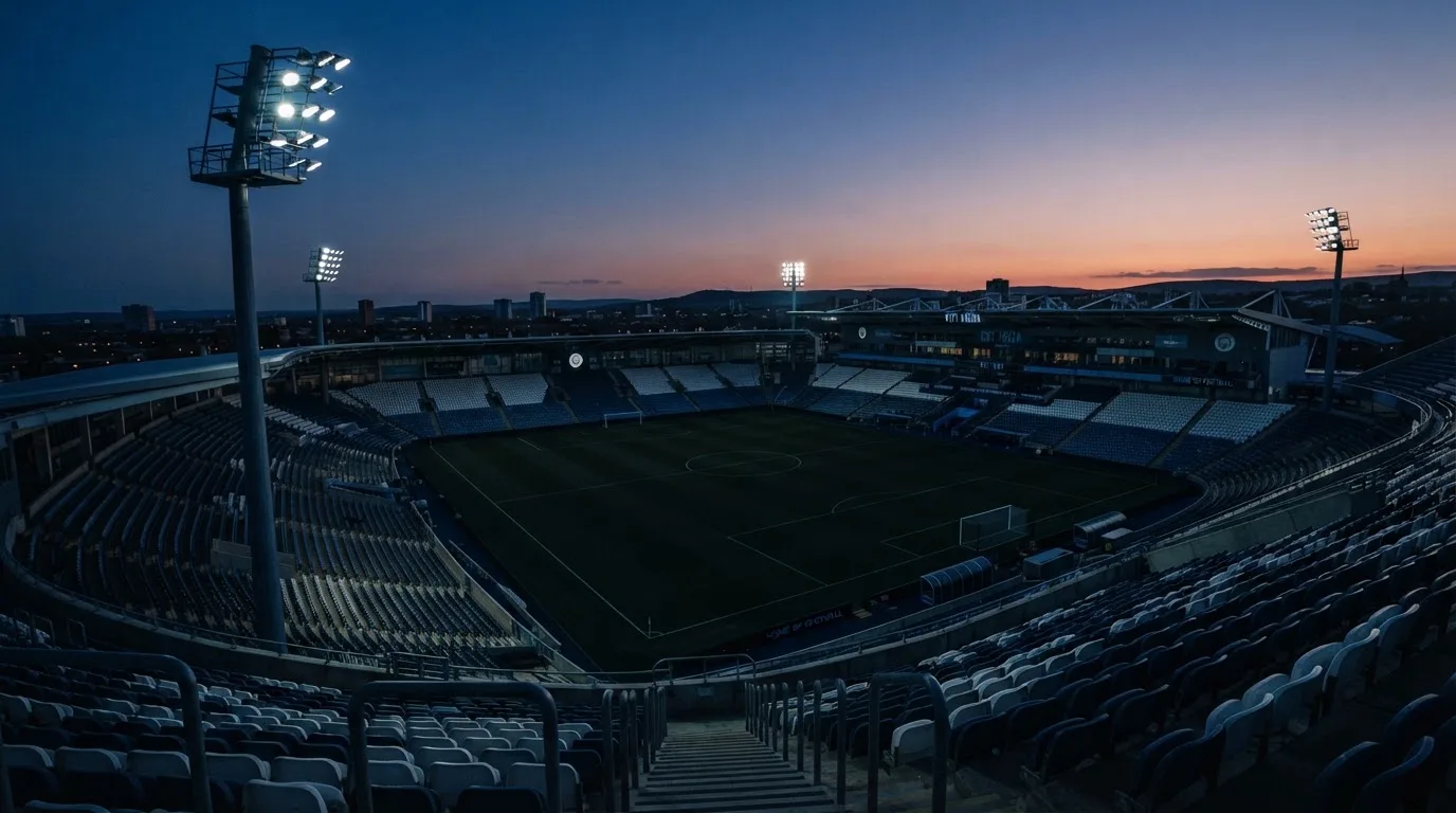 An empty football stadium with floodlight masts at dusk