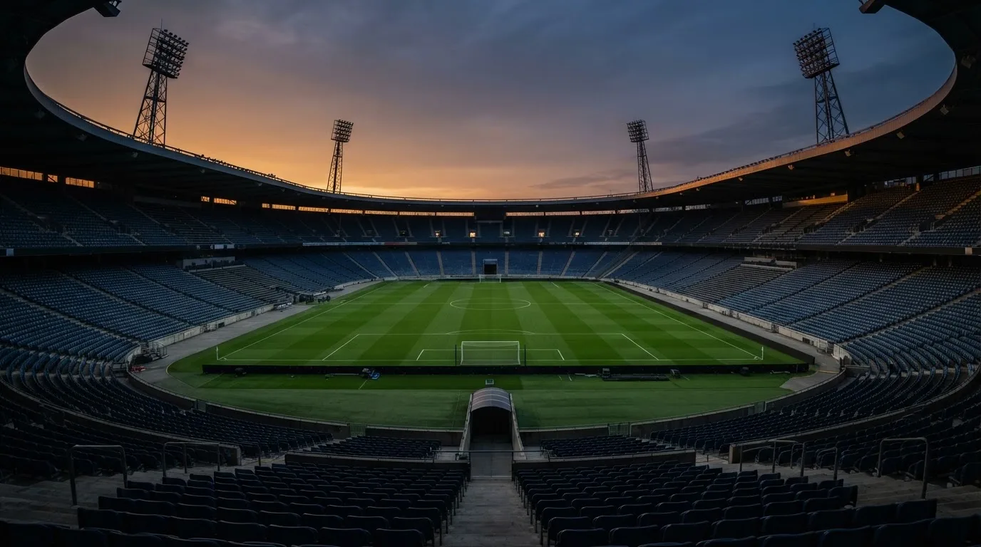 An empty football stadium with floodlight masts at dusk