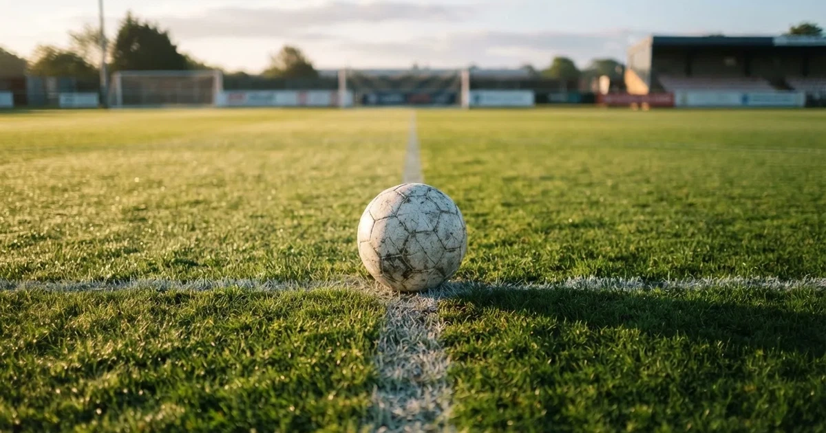A ball on the centre spot of a grass pitch in morning light
