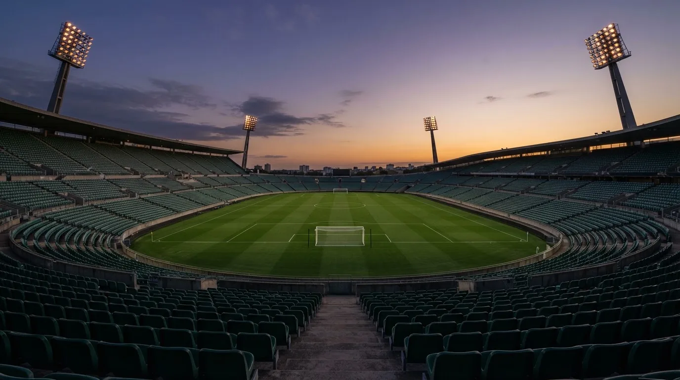An empty football stadium with floodlight masts at dusk