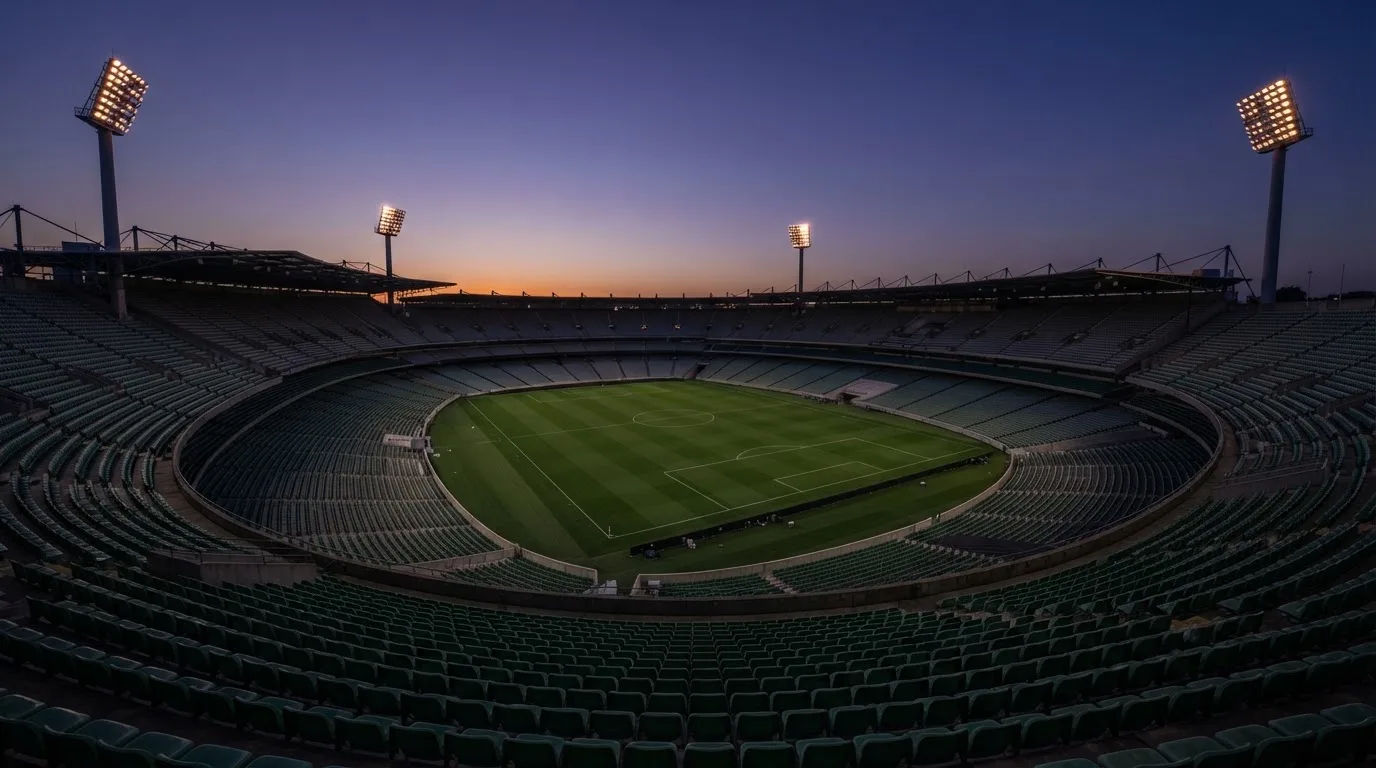 An empty football stadium with floodlight masts at dusk