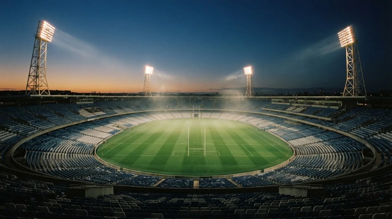 An empty football stadium with floodlight masts at dusk