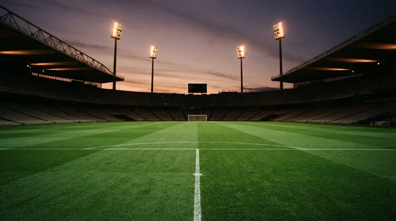 An empty football stadium with floodlight masts at dusk